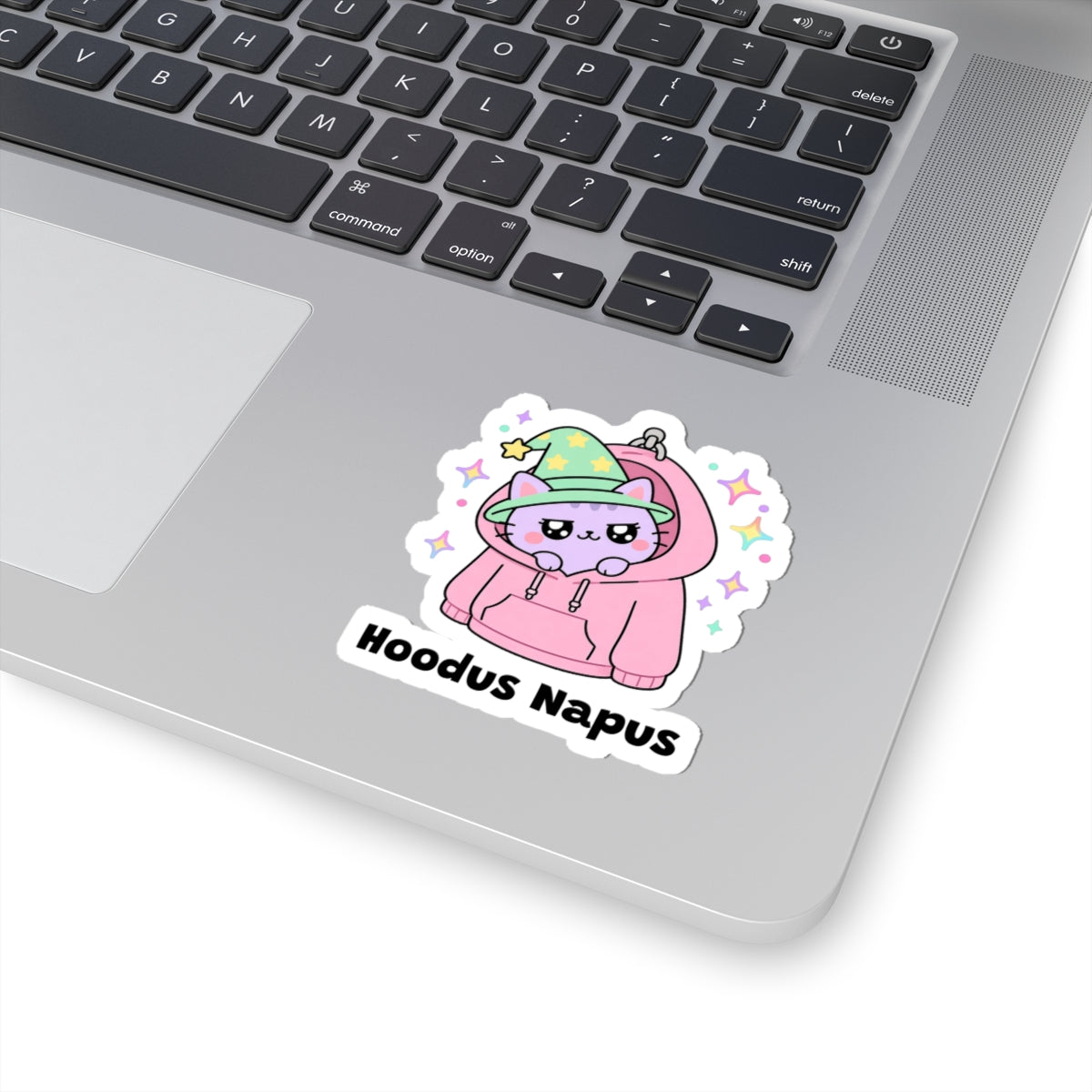 Hoodus Napus wizard cat sticker stuck on a silver laptop next to the keyboard