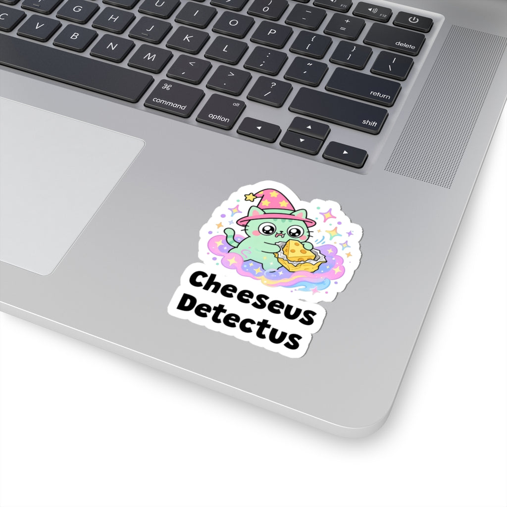 Cheeseus Detectus wizard cat sticker stuck on a silver laptop next to the keyboard