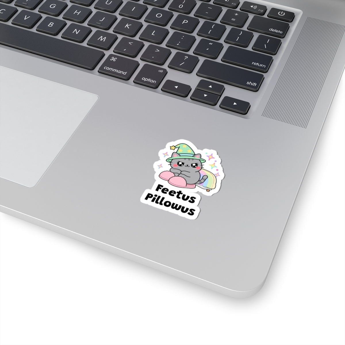 Feetus Pillowus wizard cat sticker stuck on a silver laptop next to the keyboard