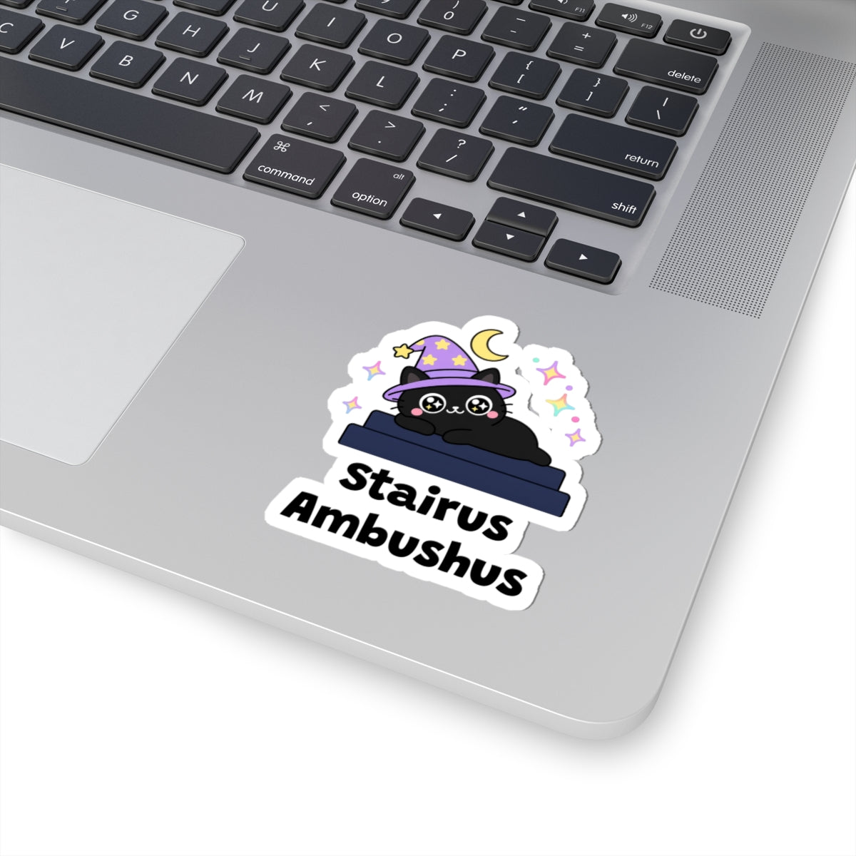 Stairus Ambushus wizard cat sticker stuck on a silver laptop next to the keyboard