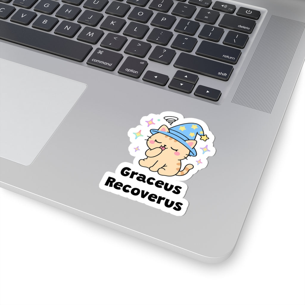 Graceus Recoverus wizard cat sticker stuck on a silver laptop next to the keyboard