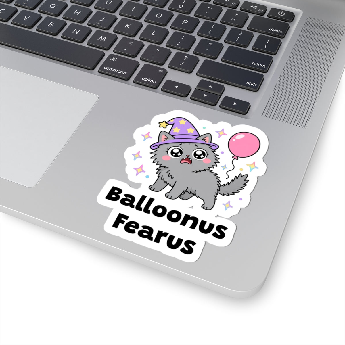 Balloonus Fearus wizard cat sticker stuck on a silver laptop next to the keyboard
