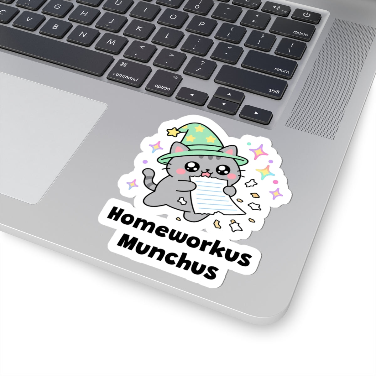 Homeworkus Munchus wizard cat sticker stuck on a silver laptop next to the keyboard