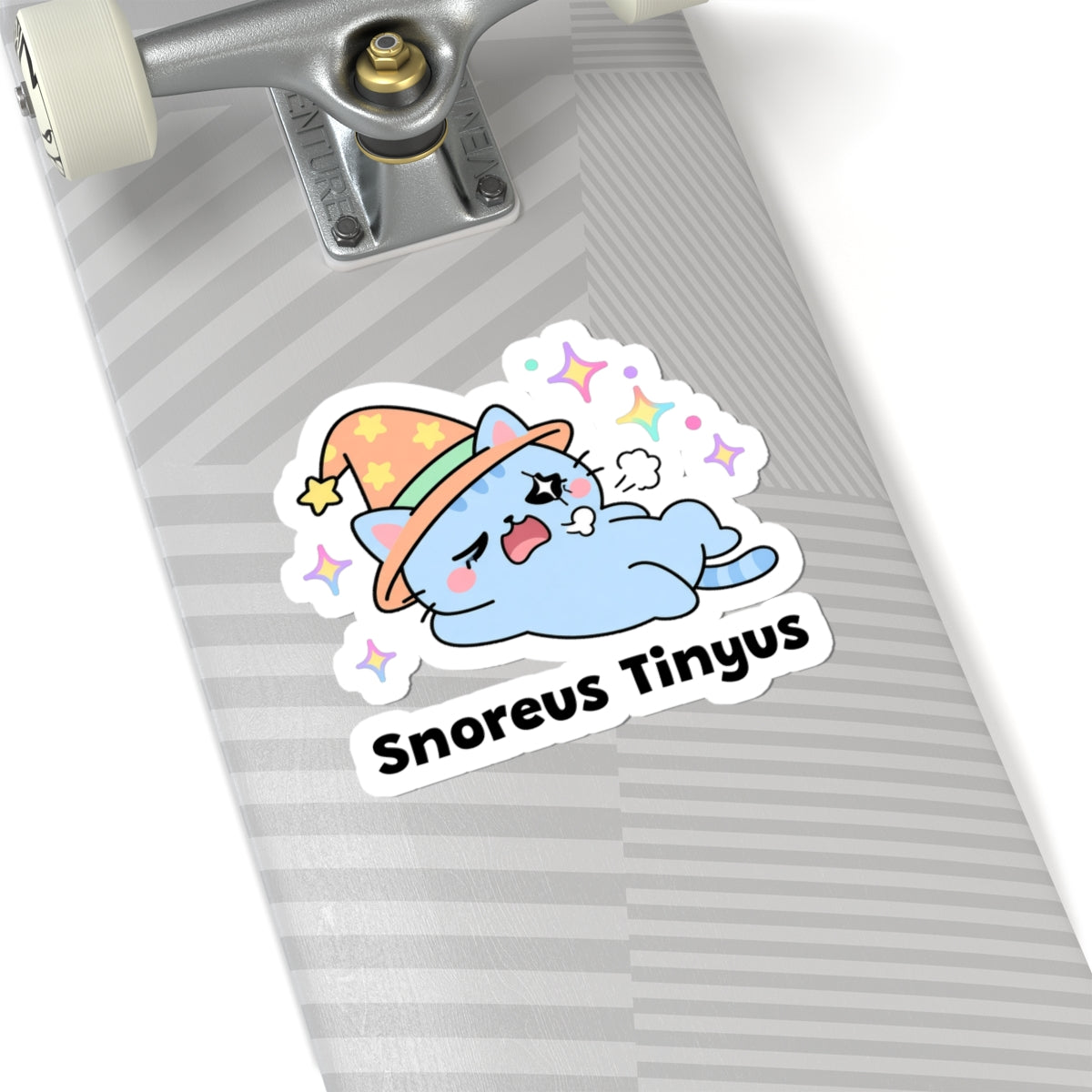 Snoreus Tinyus wizard cat sticker on a grey skateboard deck near the truck