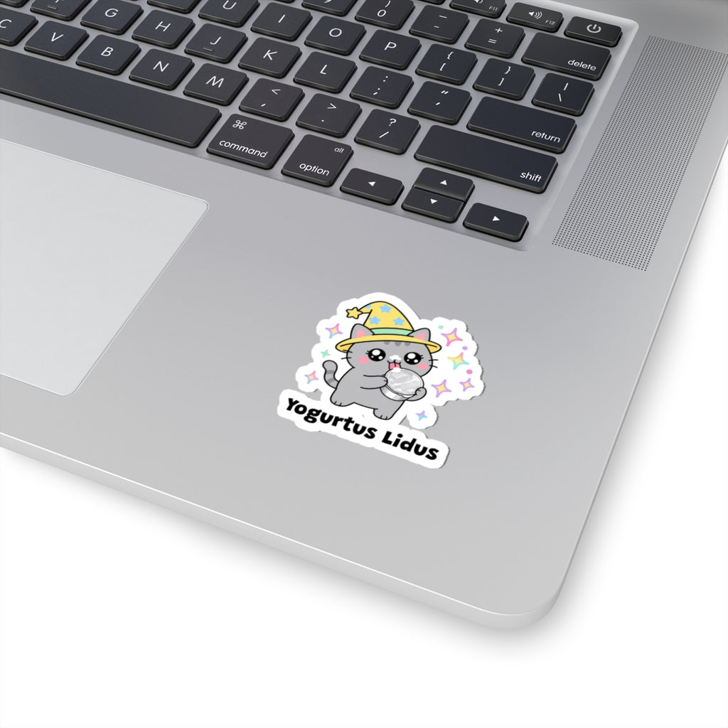 Yogurtus Lidus wizard cat sticker stuck on a silver laptop next to the keyboard
